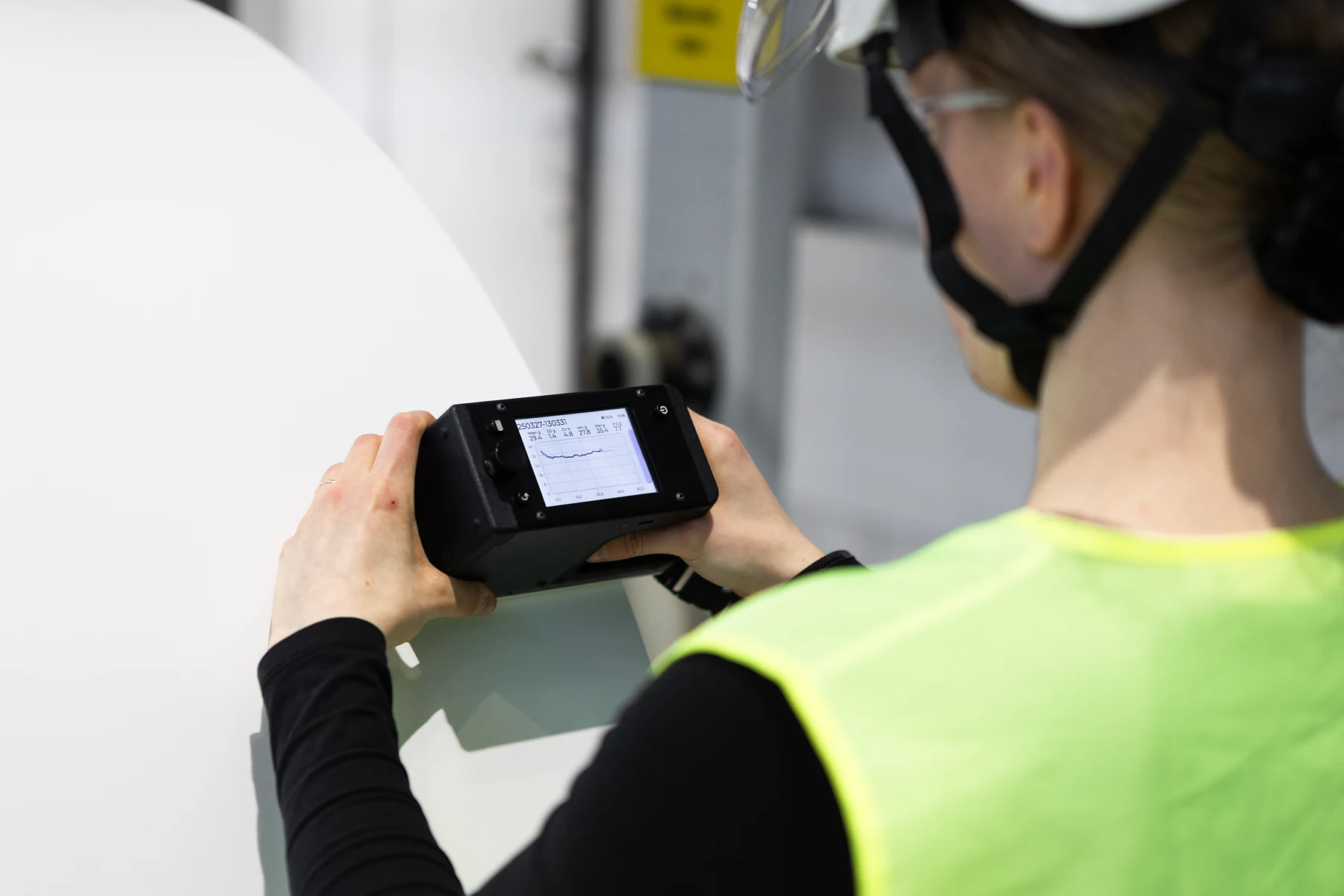 Operator holding the Tapio RQP Live against a paper roll, with the hardness profile and roll statistics on its display.