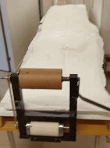A set of wide paper strips laid out lengthwise on a table, with a cutter device used to prepare them for testing purposes.